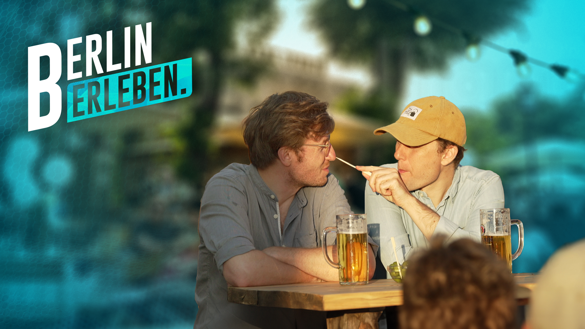 Zwei Männer schauen sich lächeln an, im Vordergrund sind zwei Bierkrüge zu sehen. (Bild: rbb/Arne Jannsen/Maximilian Fischer)