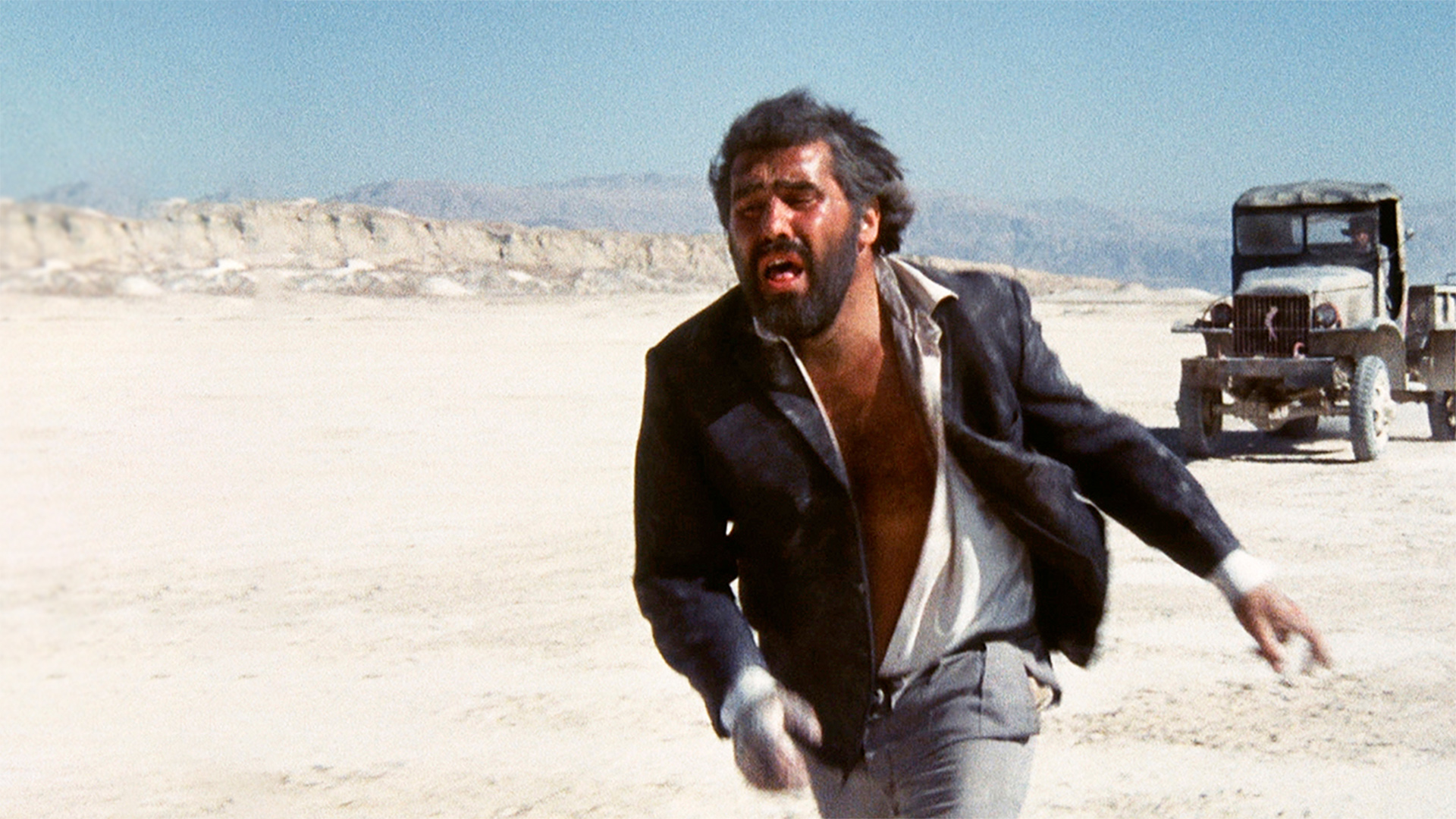 Mario Adorf in dem Kultklassiker von Roland Klick "Deadlock" rennt schreiend durch die Wüste, hinter ihm ist ein alter Geländewagen | Bild: rbb/Filmgalerie 451: 