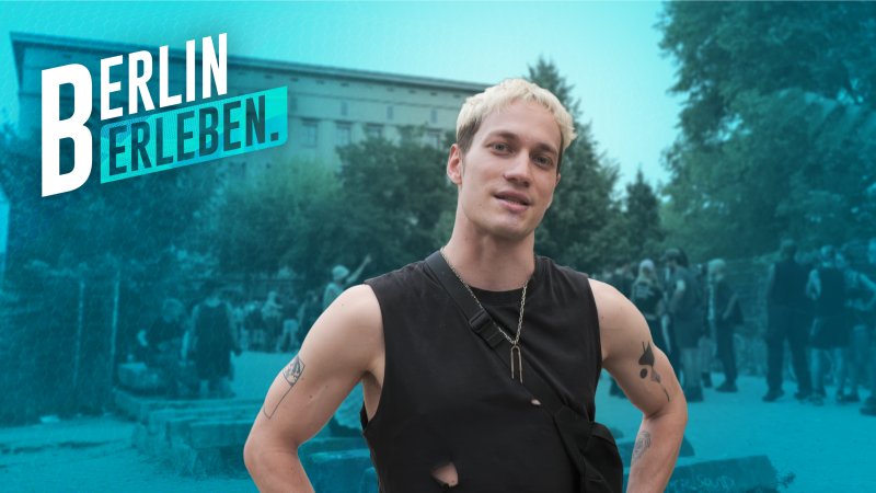Junger Mann mit blond gefärbten Haaren und zerrissenem schwarzen T-Shirt steht lässig vor einer Menschenmenge am Berliner Club Berghain in Friedrichshain.