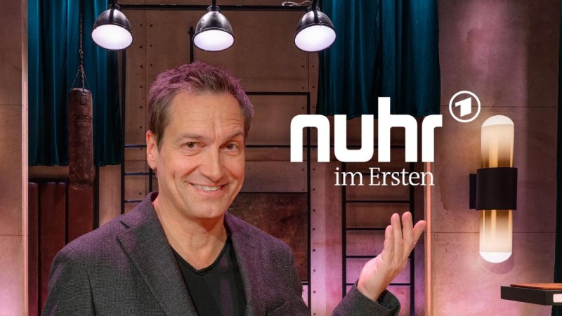 Porträtbild des Satirikers Dieter Nuhr mit gehobener Hand.