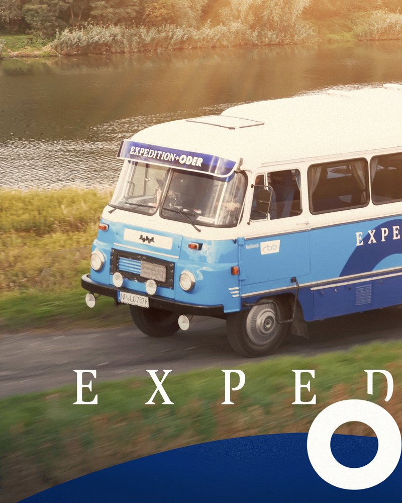 Das Vorderteil eines himmelblauen Robur-Busses mit weiĂźem Dach.