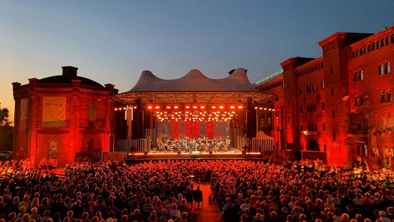 Publikum sitzt bei Sonnenuntergang vor der großen Open-Air-Bühne der Elblandfestspiele in Wittenberge bei Sonnenuntergang (Quelle: rbb/Monika Schmitt)