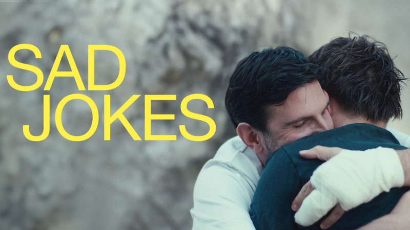 Zwei Männer umarmen sich innig; einer trägt einen Verband am Arm, Szen aus dem Film „Sad Jokes“.