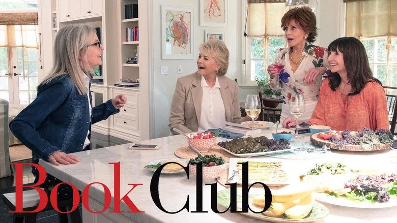 Vier Frauen sitzen gemeinsam an einem gedeckten Küchentisch und unterhalten sich lebhaft, Szene aus „Book Club“.