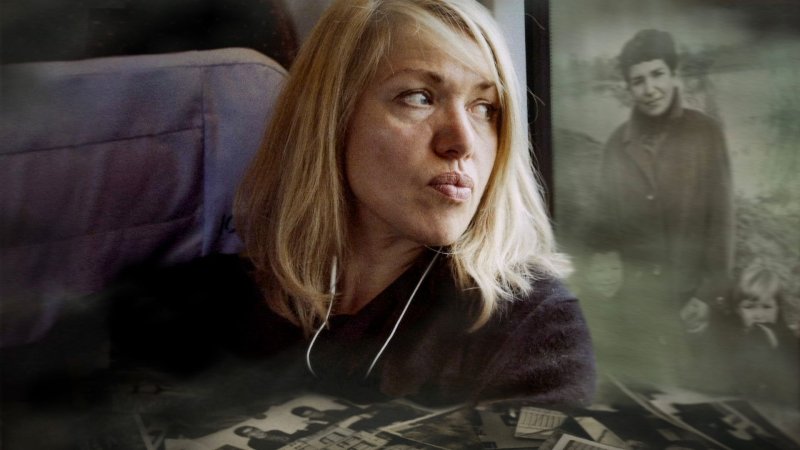 Eine blonde Frau sitzt nachdenklich am Fenster eines Zuges; daneben sind verschwommene historische Familienfotos eingeblendet. Zum Dokumentarfilm: Liebe Angst