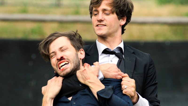 Junger Mann im Anzug (Florian Stetter) hält von hinten seinen aus der Nase blutenden Bruder (Franz Dinda) im Würgegriff | Bild: rbb/Oliver Feist