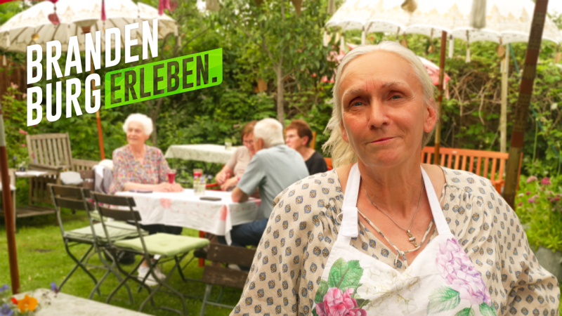 Cafébetreiberin des Kuchengarten in Zietenhorst, im Hintergrund sitzen Gäste an einem Tisch.