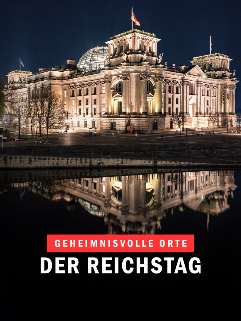 Der beleuchtete Reichstag in Berlin spiegelt sich nachts im Wasser.